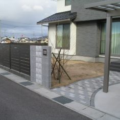 アプローチにはコンクリート舗装材のインターロッキングを２色使用。門柱から建物の間のスペースは芝庭となっています。