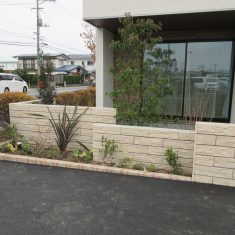 こちらは石積みの質感を表現したブロックを３連にしています。駐車場側の植栽枡には存在感のあるニューサイラン、低木類や下草等を植えています。